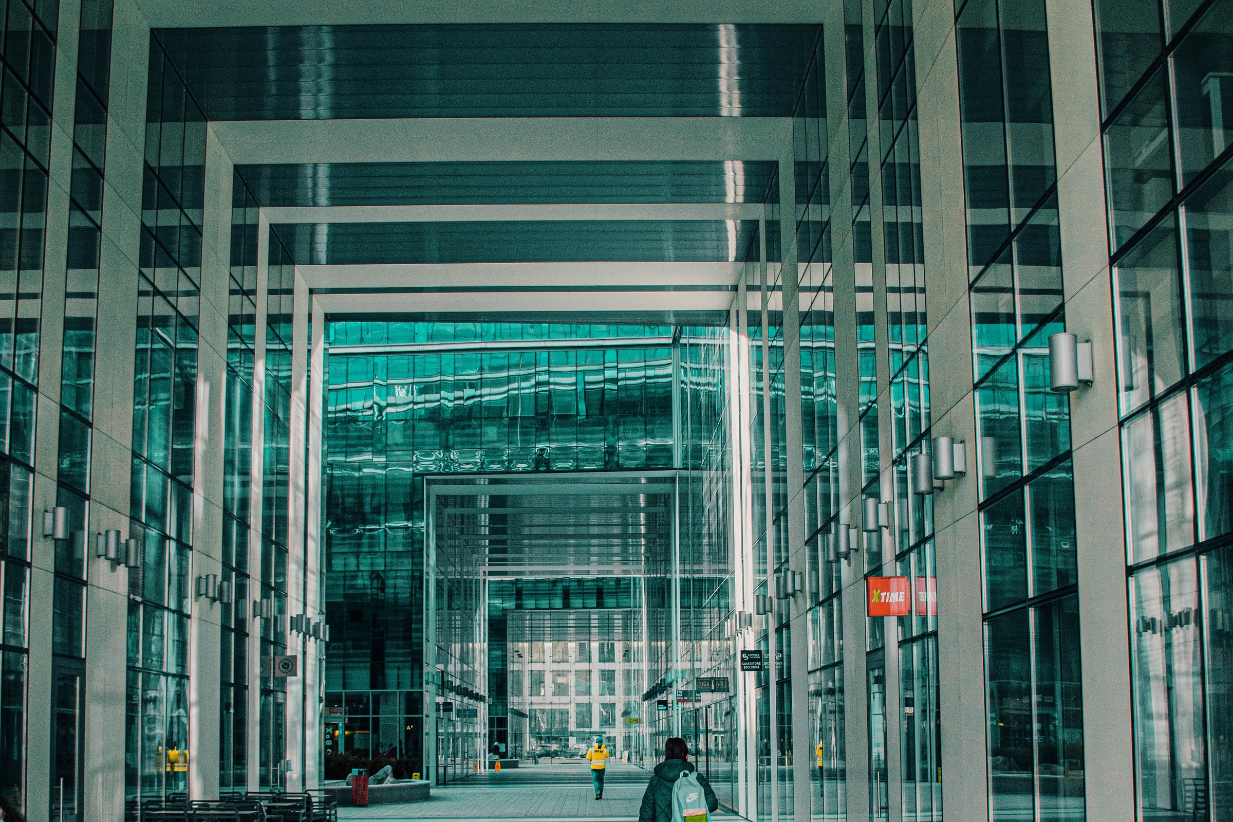Person walking through a modern glass corridor.