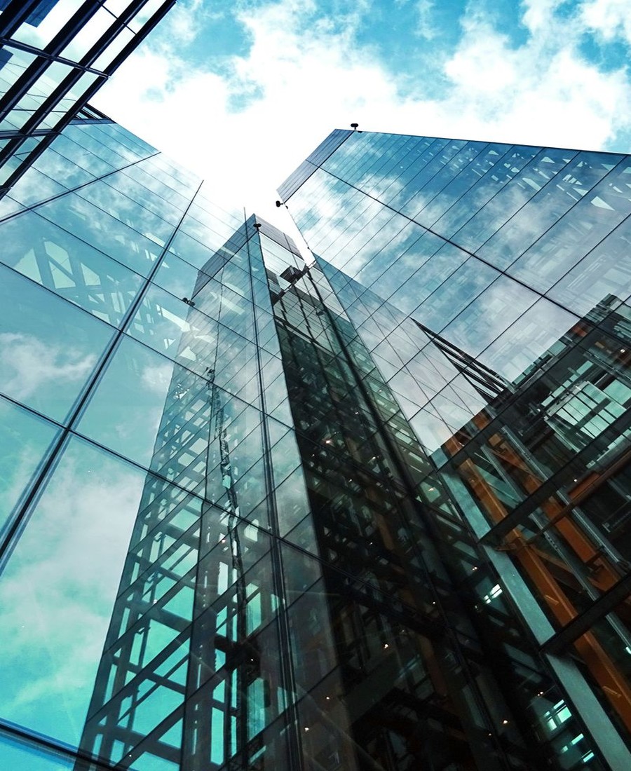 Low-angle view of modern glass skyscrapers against a bright sky.